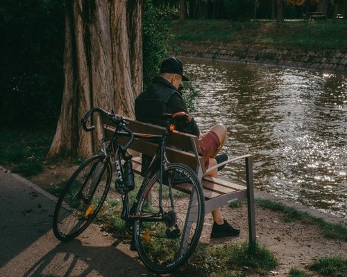 A person taking a short break on a park bench next to a bicycle path